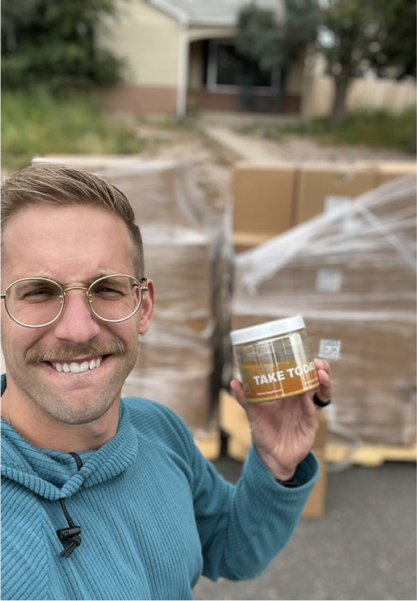 Founder Fabian proudly holding Take Today's Habit Blend in front of a shipment. A commitment to quality and wellness delivered to your doorstep. Trust in every jar.